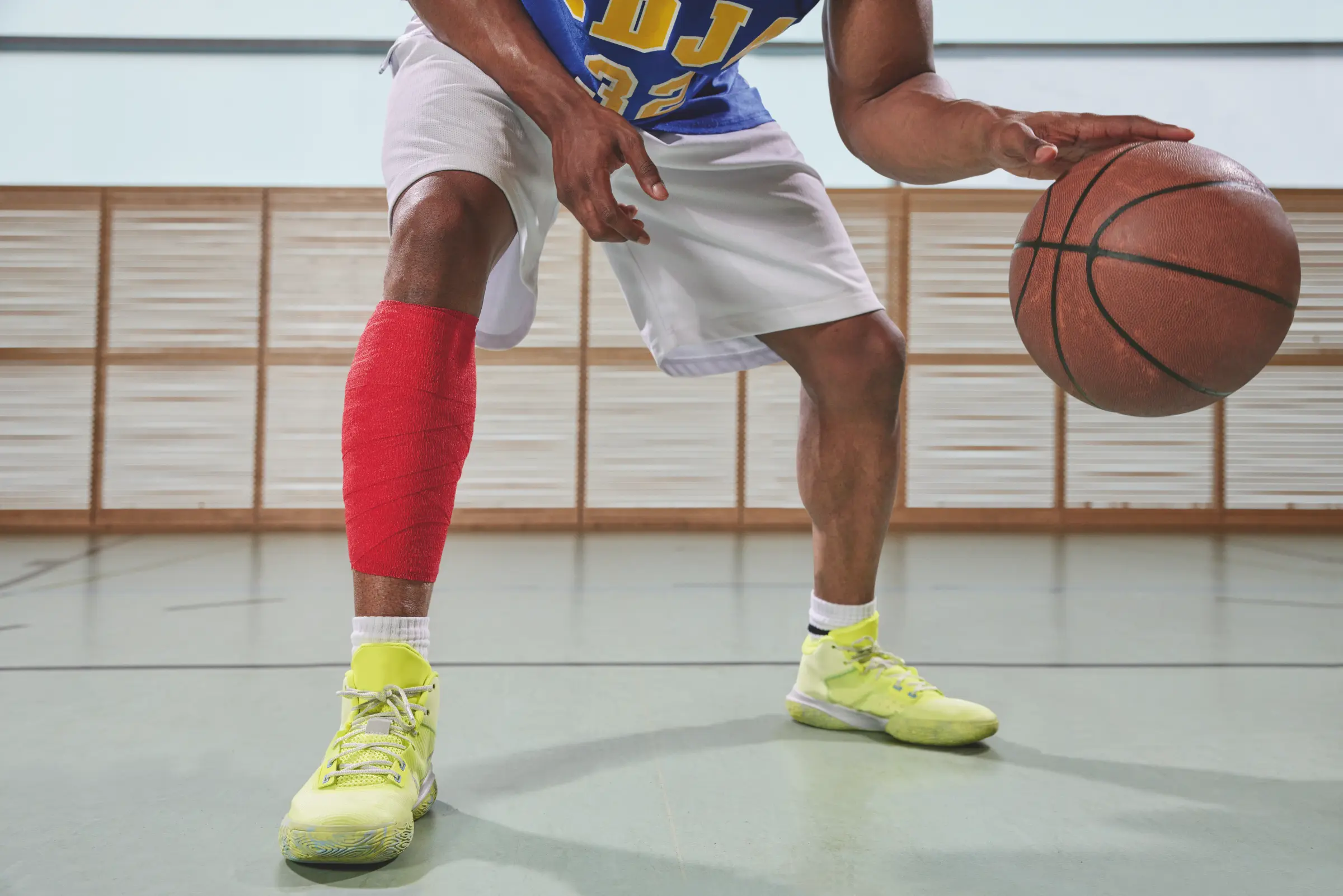 Bande Co-Plus sans Latex utilisée par un joueur de basketball pour le soutien musculaire et articulaire.
